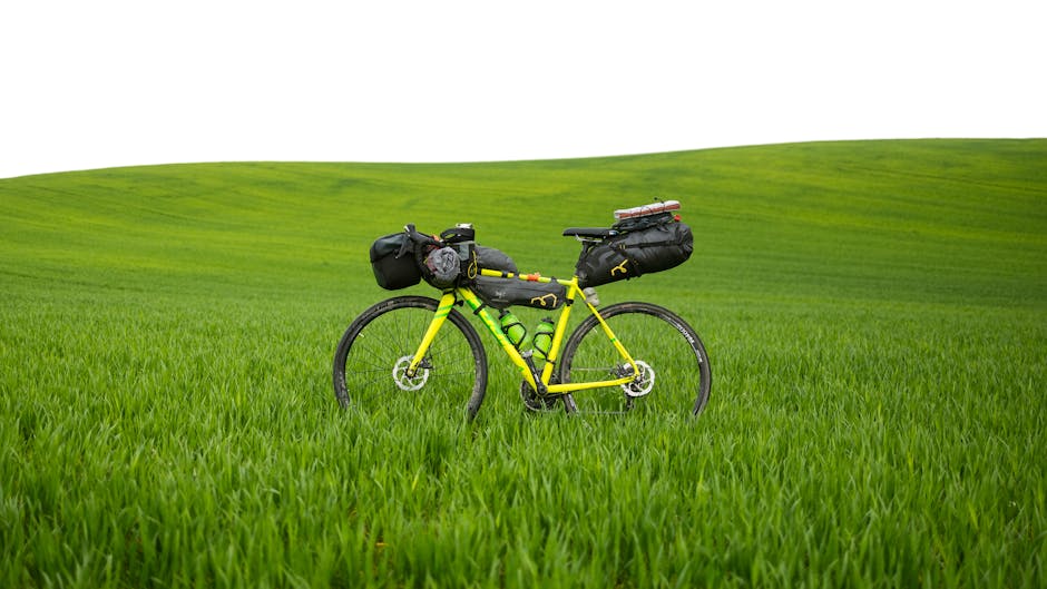 A bright yellow bike loaded for bikepacking in a lush green field, signifying adventure.
