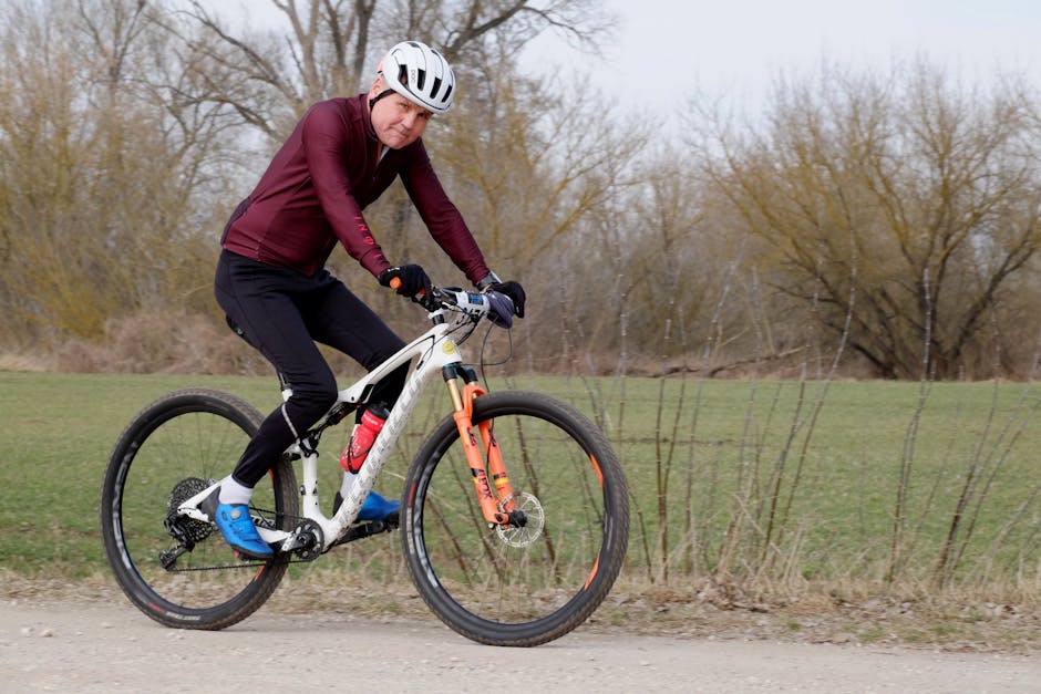 An adult cyclist riding a mountain bike on a gravel path surrounded by nature, showcasing fitness and outdoor activity.