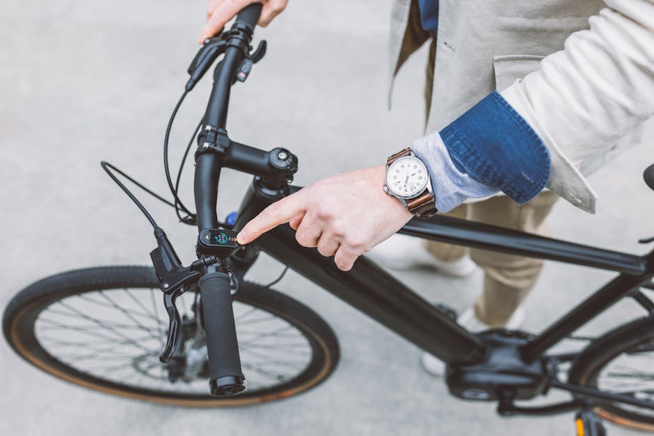 Caucasian man with a wristwatch touches the screen on a black electric bicycle, showcasing modern technology in transportation.